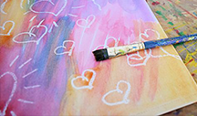 Crayon Resist A paintbrush and painted canvas with hearts