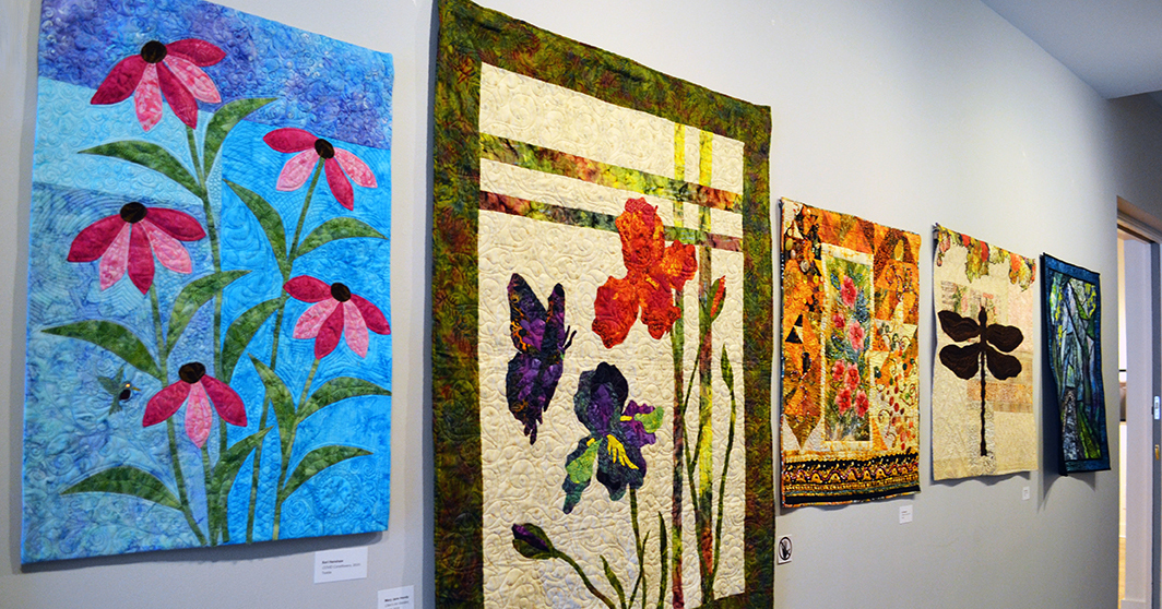 Material Girls Quilt Guild Colorful floral quilts are hung in the gallery.